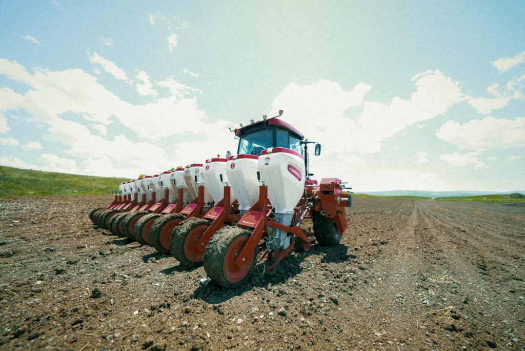A modern tractor prepares soil in the expansive farmlands of Erzurum, Türkiye under a clear blue sky.